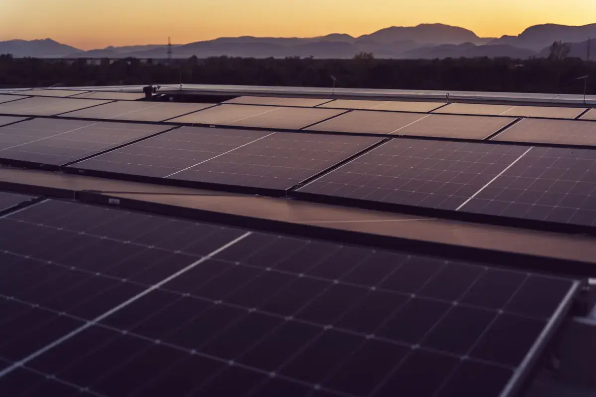 Konzeptvisualisierung: Solarmodule bei Sonnenuntergang vor Bergsilhouette