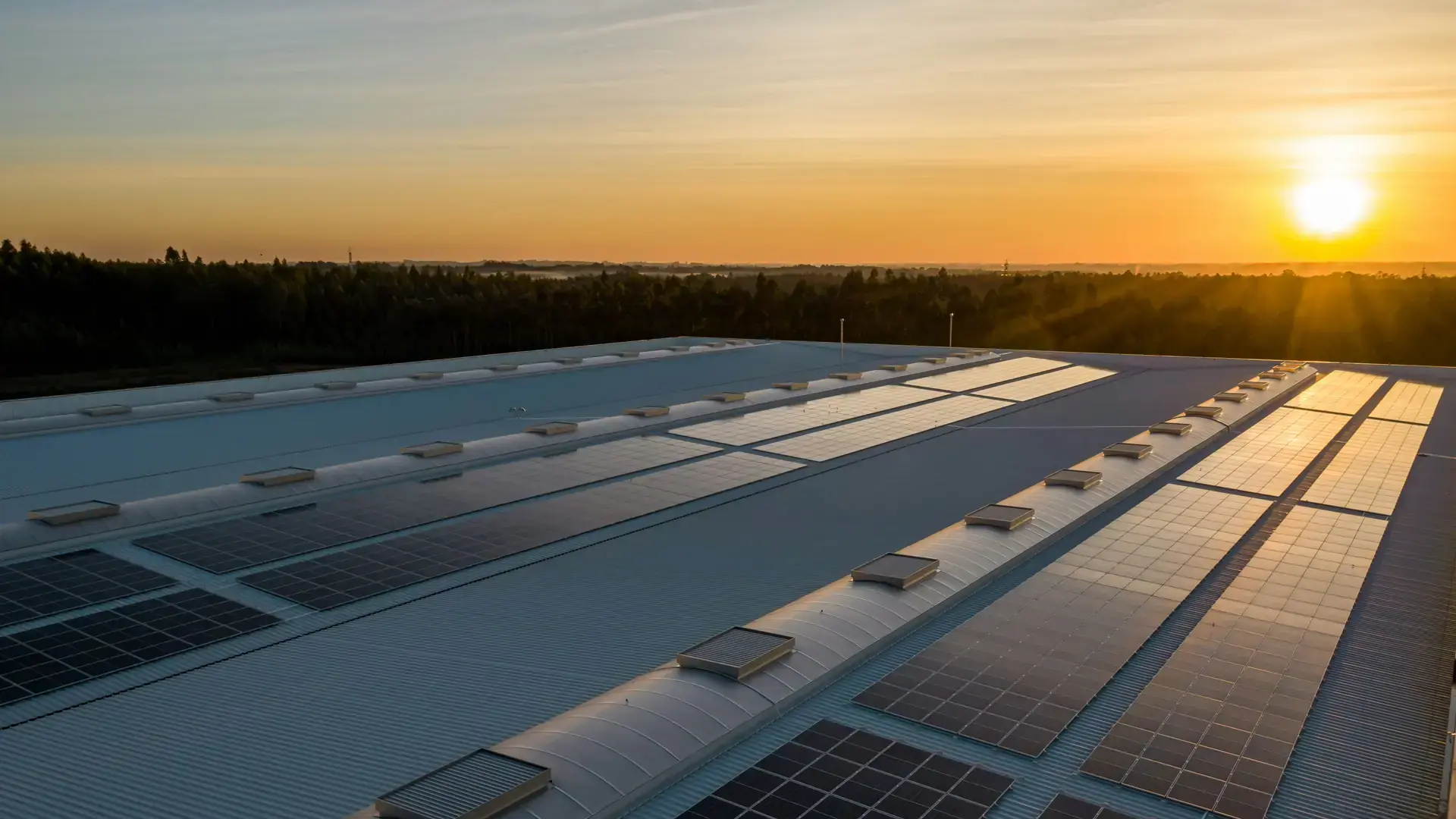 Konzeptvisualisierung: Luftaufnahme eines Industriedachs mit Solarmodulen bei Sonnenaufgang